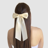 A woman with long brown hair wears a large ivory-colored bow at the back of her head, highlighting elegance and femininity. Bridal Hair Accessories Guide for Every Wedding Event.