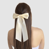 Woman wearing ivory satin hair bow with long tails, part of women's hair accessories collection