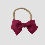 Azalea grosgrain Kayla hair bow on a nude nylon headband against a white background