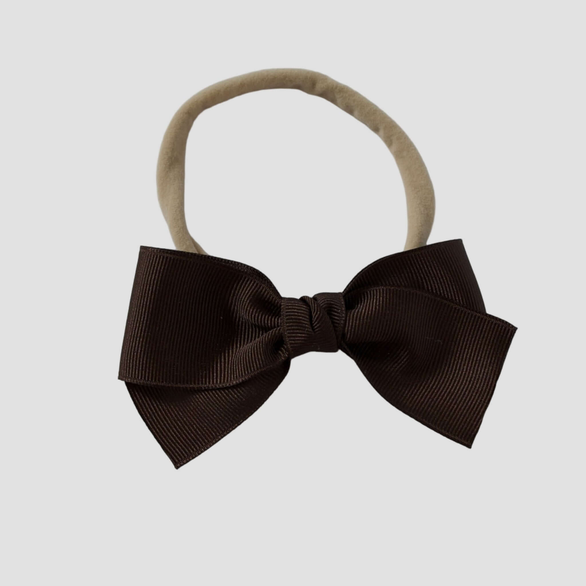 Brown hair bow on a nude nylon headband against a white background