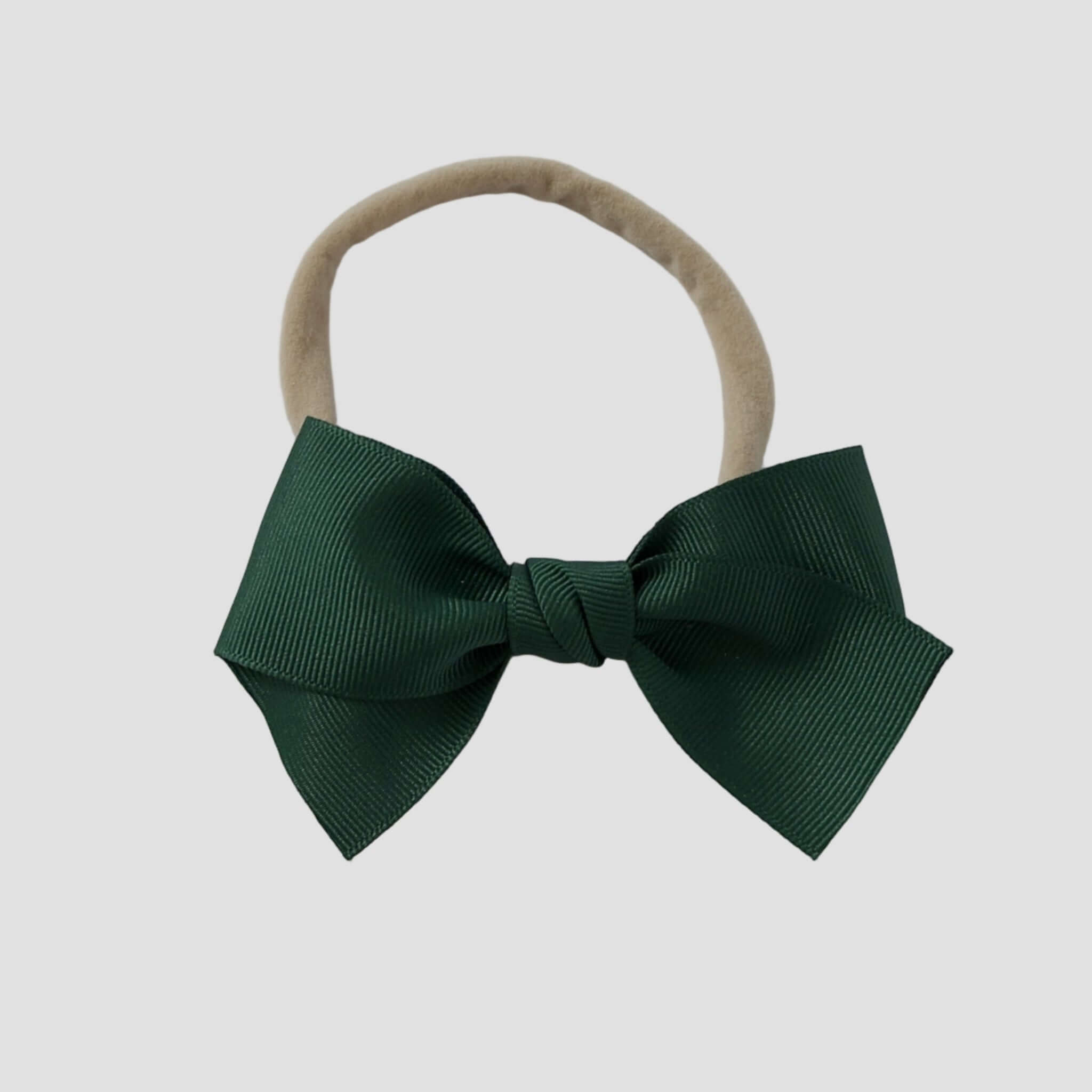 Forest green grosgrain Kayla hair bow on a nude nylon headband against a white background