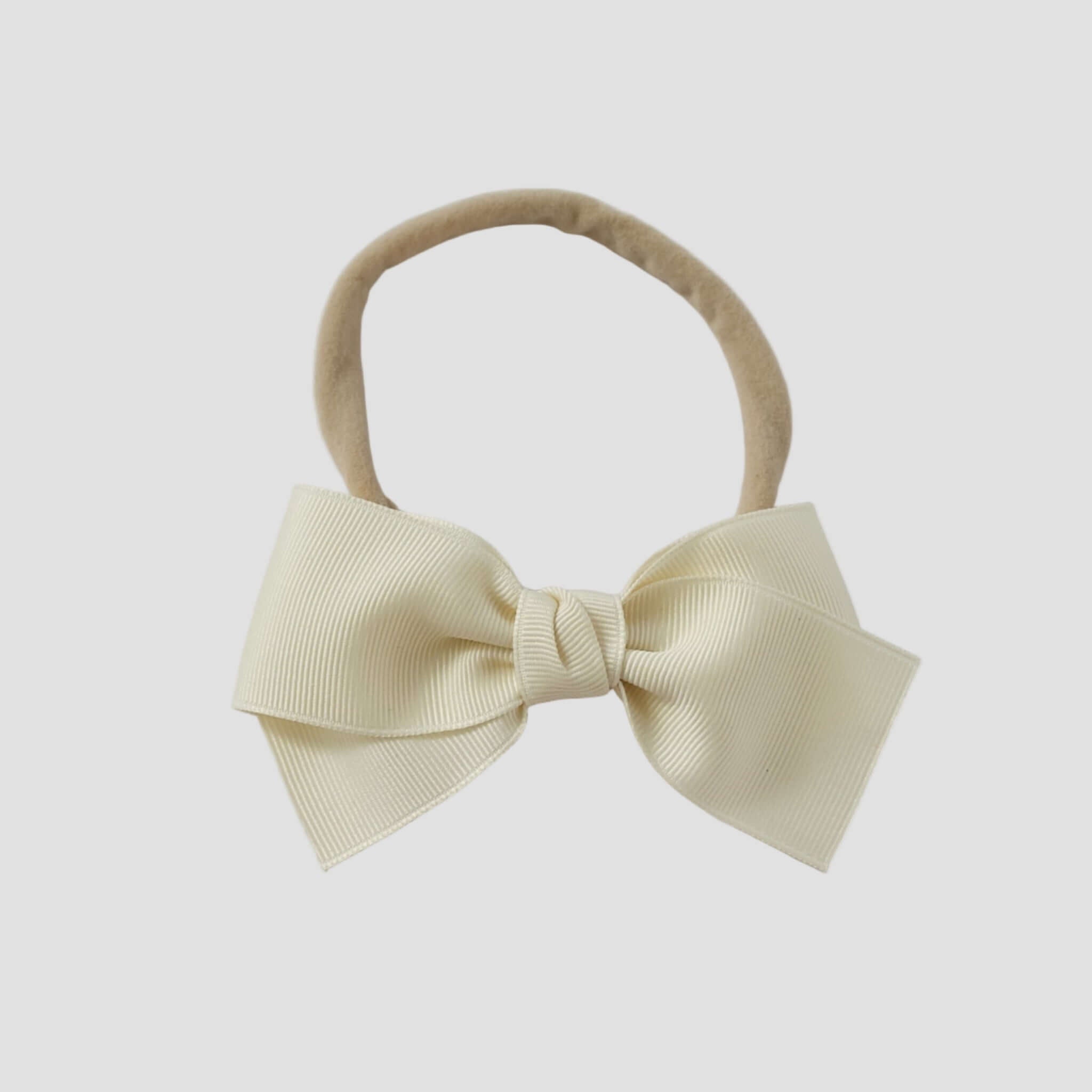 Ivory grosgrain bow on a nude nylon headband on a white background