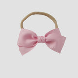Light pink grosgrain Kayla hair bow on a nude nylon headband against a white background