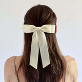 Model with long brown hair wearing a Grace satin bow in ivory bow against a white background