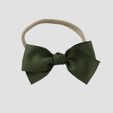 Moss green grosgrain Kayla hair bow on a nude nylon headband against a white background