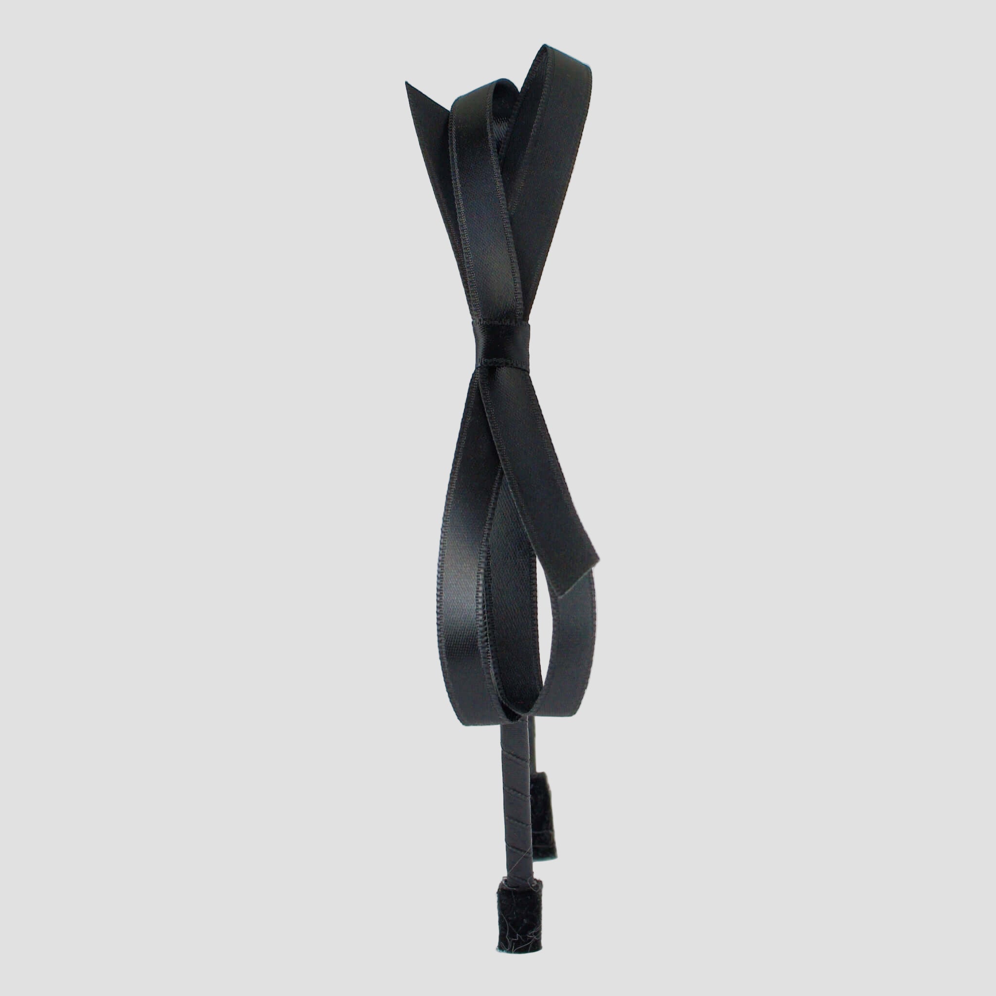 A black satin headband with a bow design in the center, displayed against a white background.