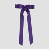 Purple bow with long ribbon tails on a white background