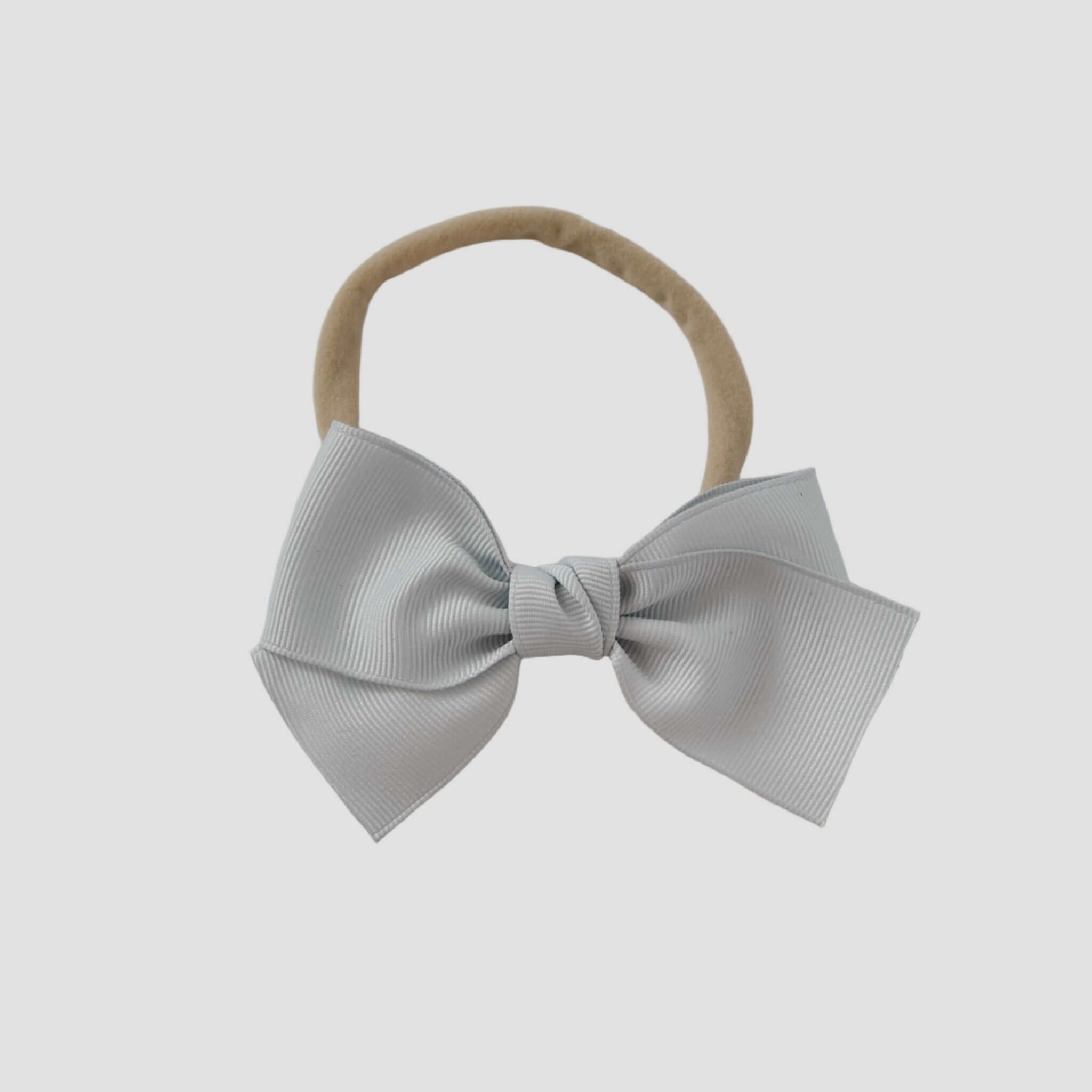 Silver grosgrain Kayla bow on a nude nylon headband against a white background
