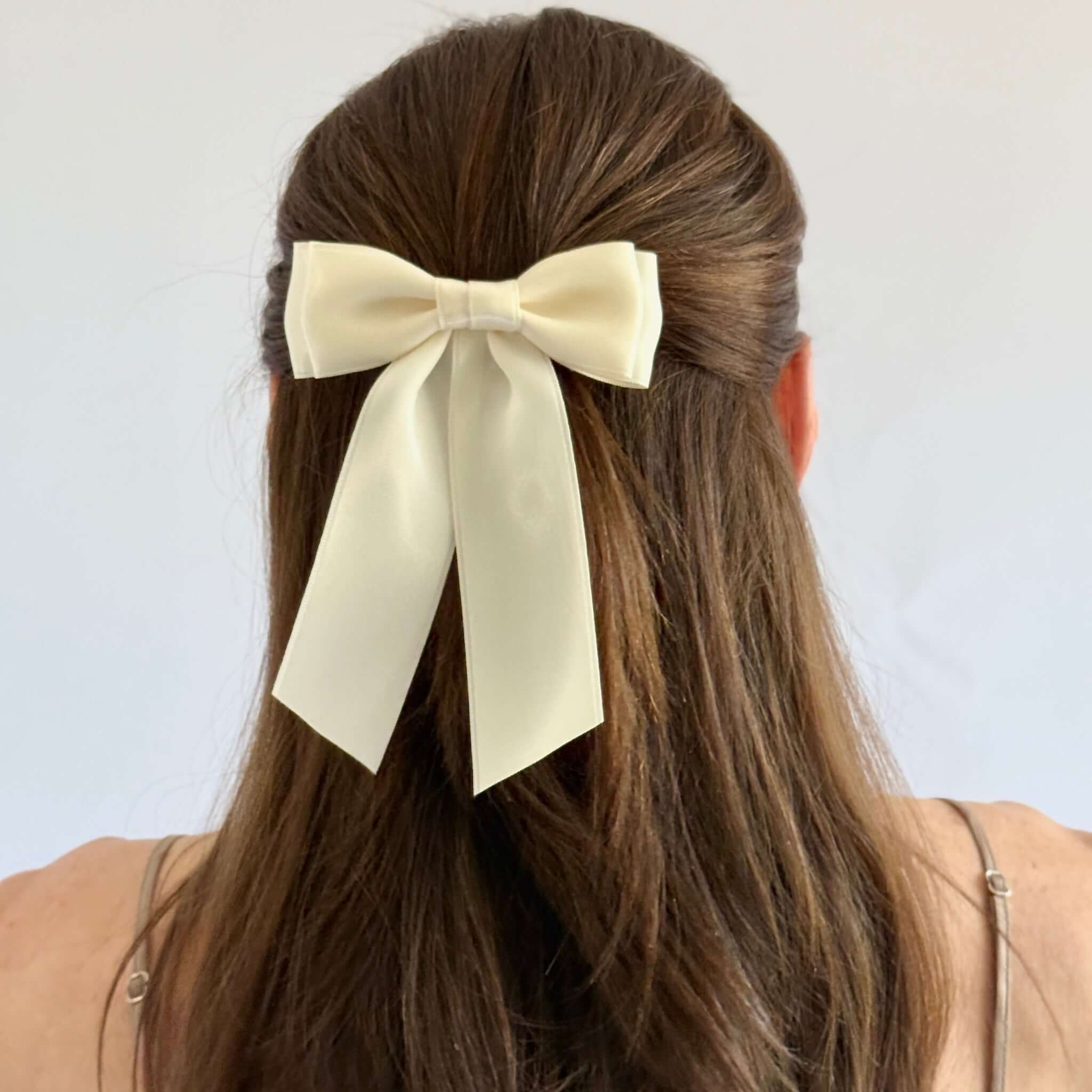 Model with brown hair wearing a hair up hairstyle with Mia satin bow in ivory.