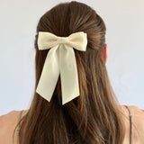 Model with brown hair wearing a hair up hairstyle with Mia satin bow in ivory.