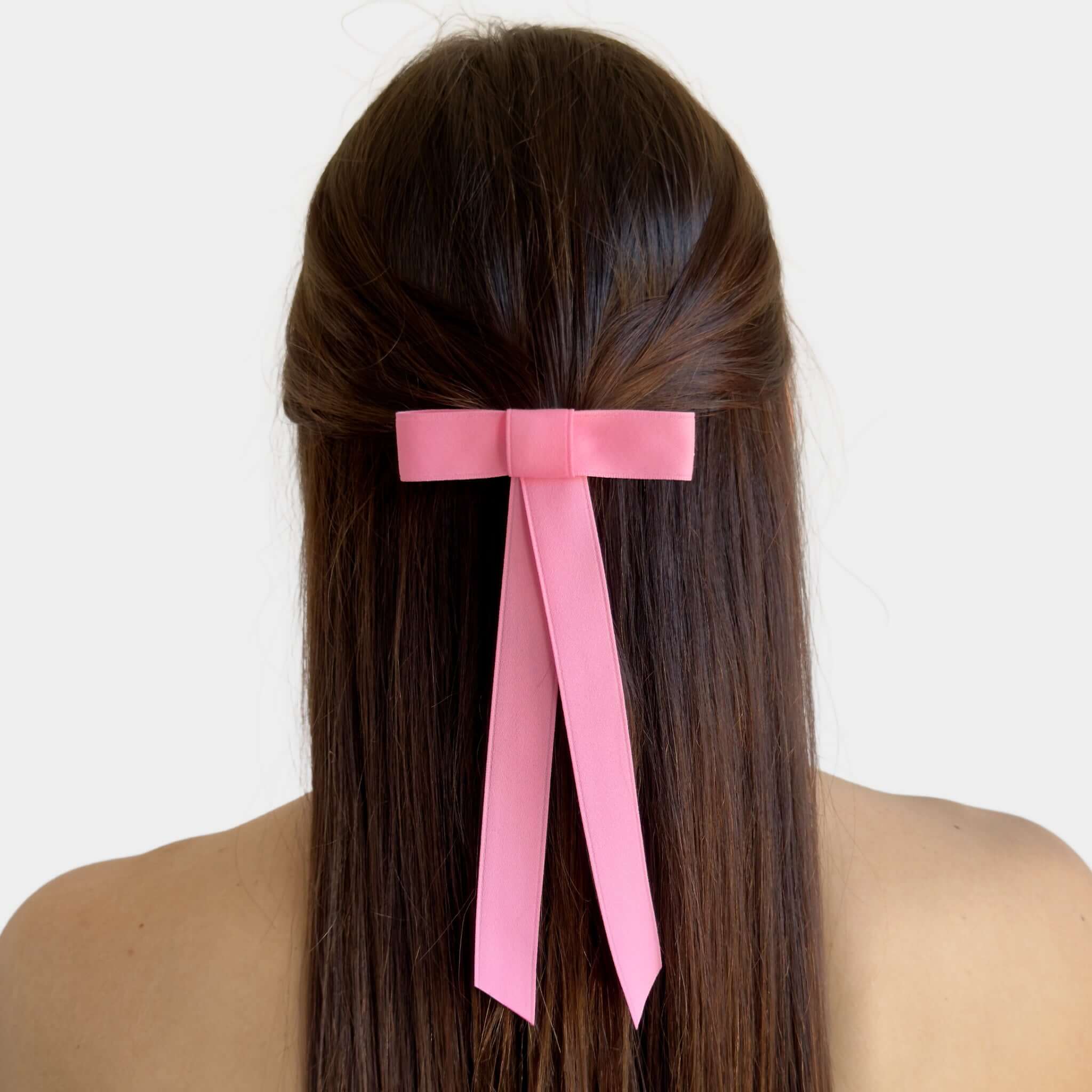 Mini matte satin hair bow in pink, handmade with eco-conscious materials, styled at the back of long hair.