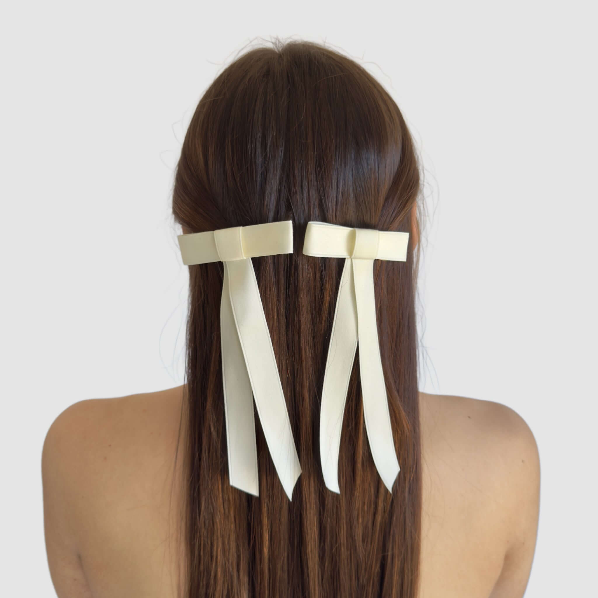 Two mini matte satin hair bows made of sustainable recycled ribbon, elegantly styled in long, straight hair.
