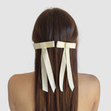 Two mini matte satin hair bows made of sustainable recycled ribbon, elegantly styled in long, straight hair.