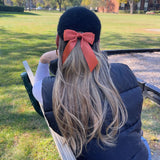 Model with blonde hair wearing a black baseball and Mia bow  in copper