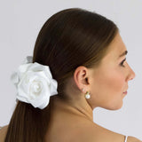 Woman wearing white satin flower claw clip in low ponytail hairstyle