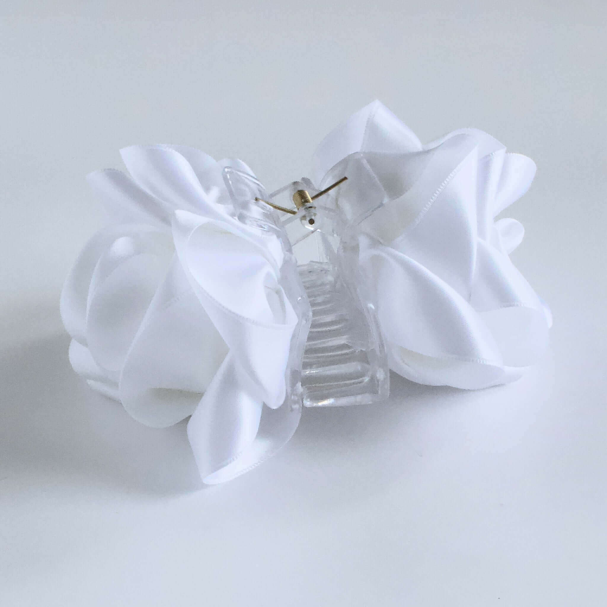 Side view of white satin flower claw clip with clear base and gold hinge