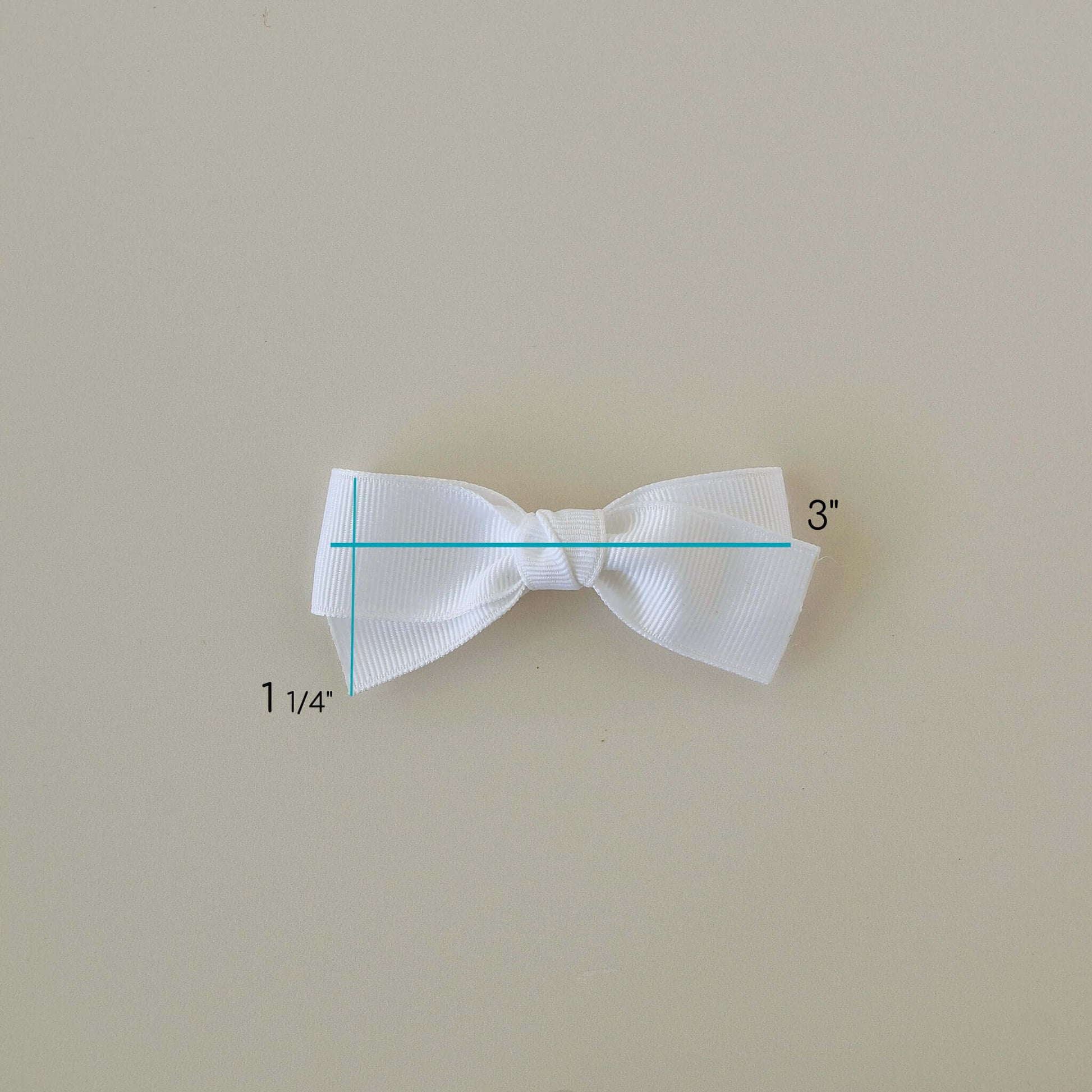 White 3 inch Grosgrain Baby Kayla Bow with alligator clip measuring guide on light background.