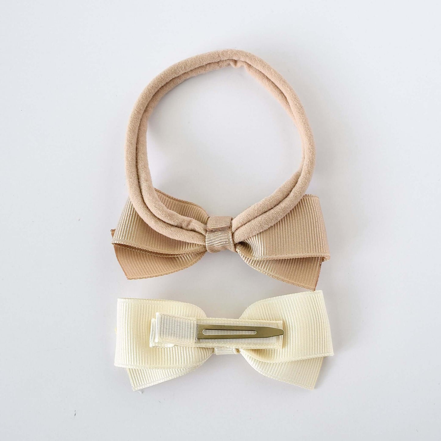 Nude nylon headband with a beige grosgrain bow and yellow grosgrain bow clip with no-slip grip for babies and young girls