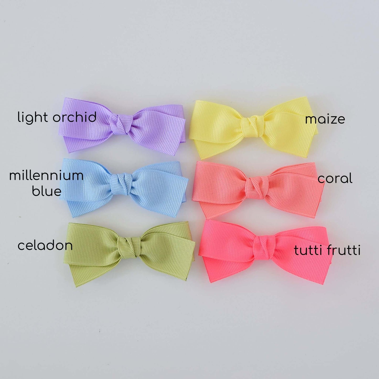 Pastel grosgrain Kayla bow clips in light orchid, maize, millennium blue, coral, celadon, and tutti frutti colors on display.