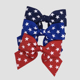 4 inch sailor hair bow with stars in navy, red and royal blue on a white background.