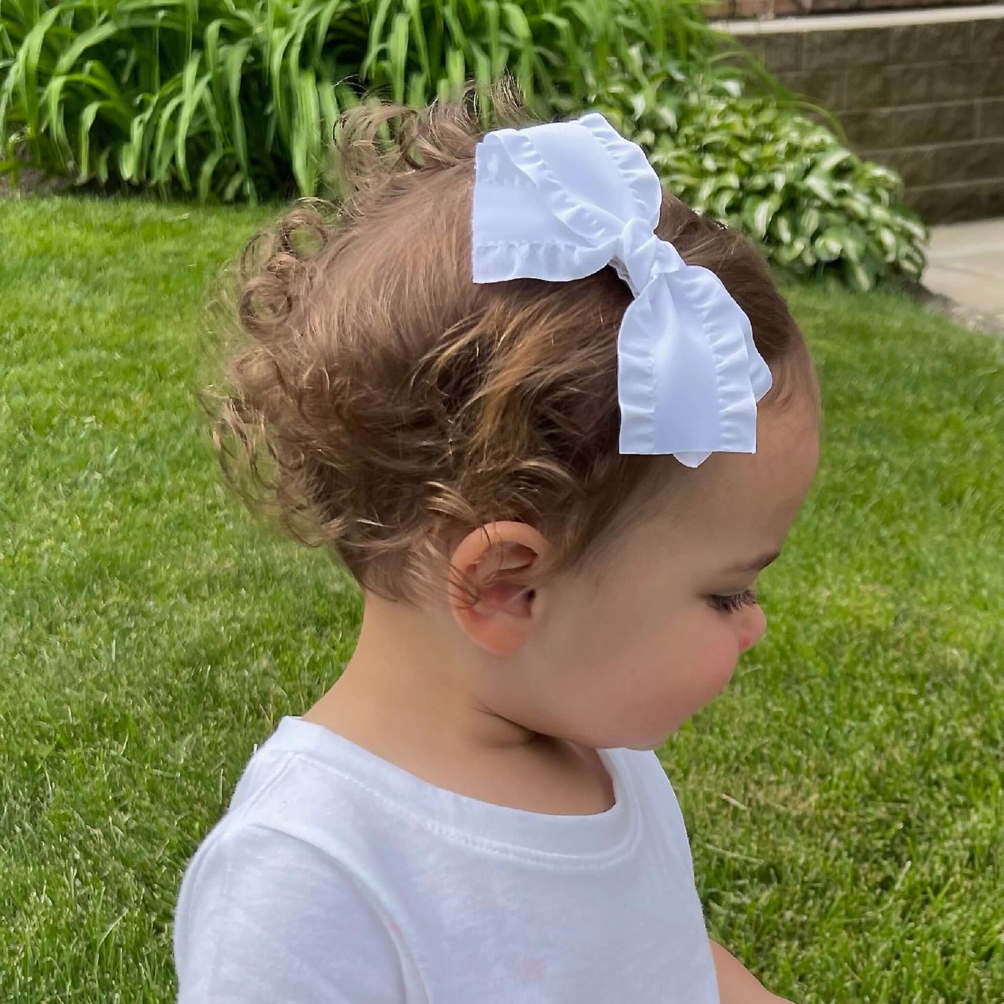 Toddler wearing 4-inch white grosgrain baby Kayla bow headband with no-slip grip, perfect accessory for baby girls and toddler outfits