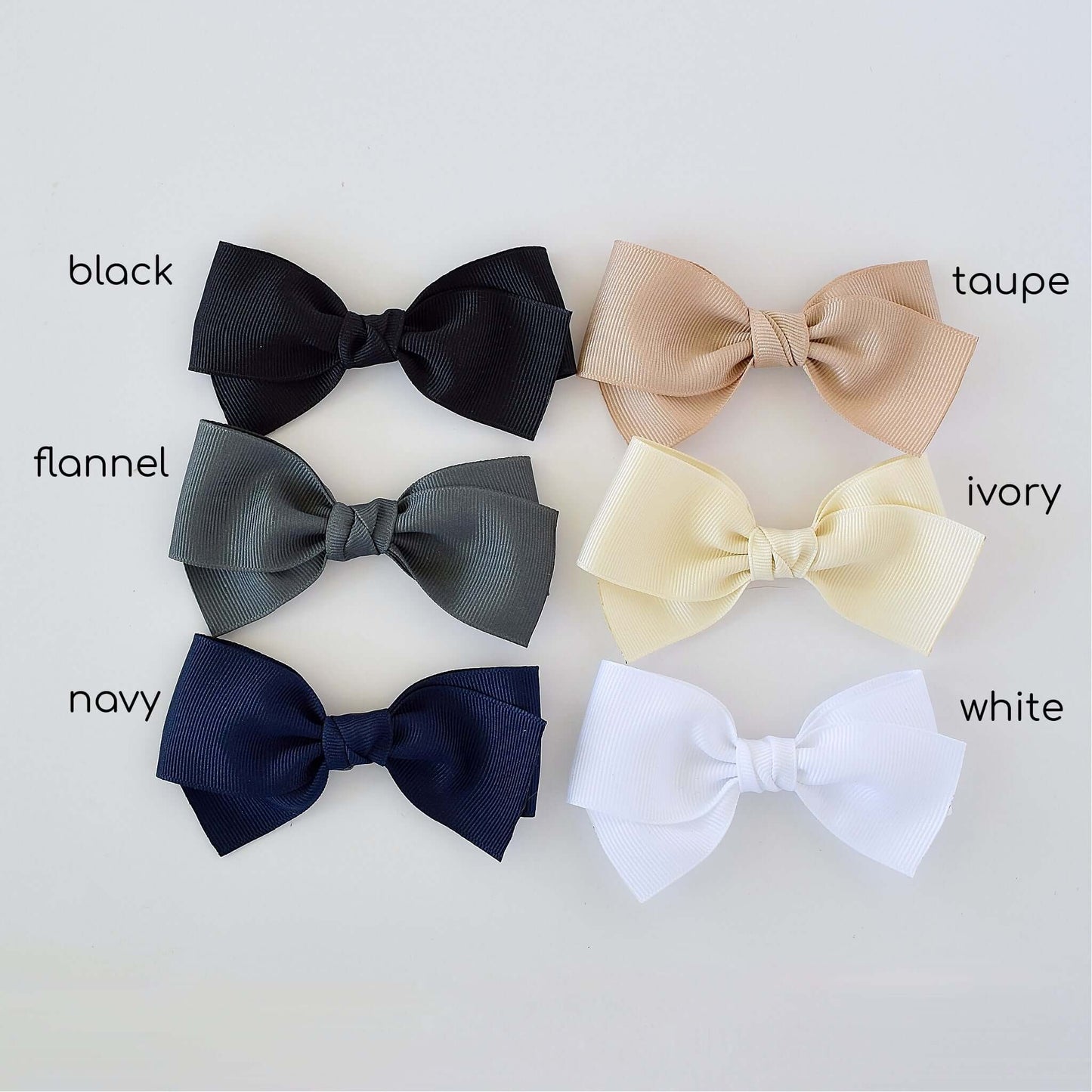 4 inch grosgrain baby Kayla bow clips and headbands in black, taupe, flannel, ivory, navy, and white colors displayed.