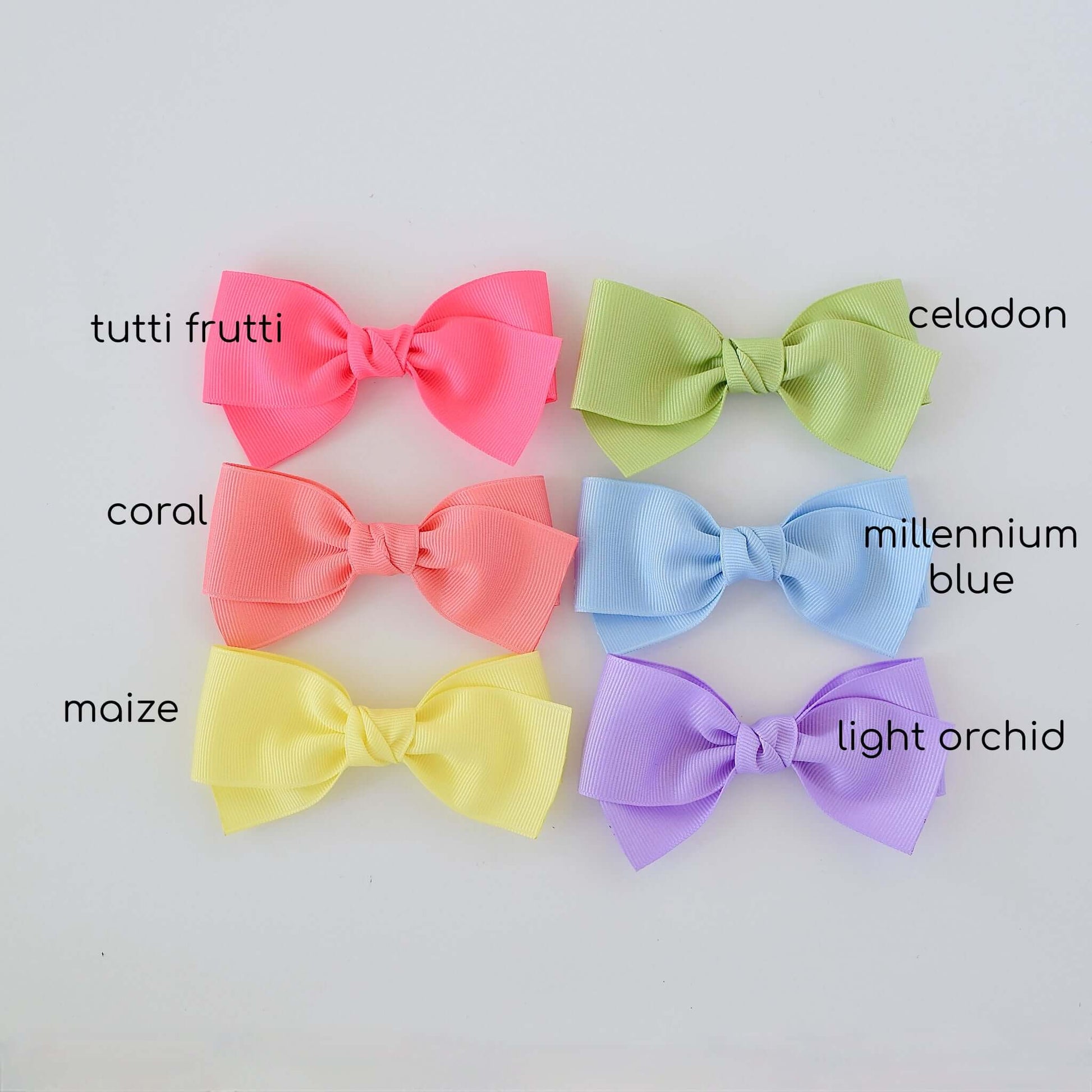 Six pastel-colored grosgrain baby Kayla hair bows in pink, green, coral, blue, yellow, and lavender displayed on a light background.