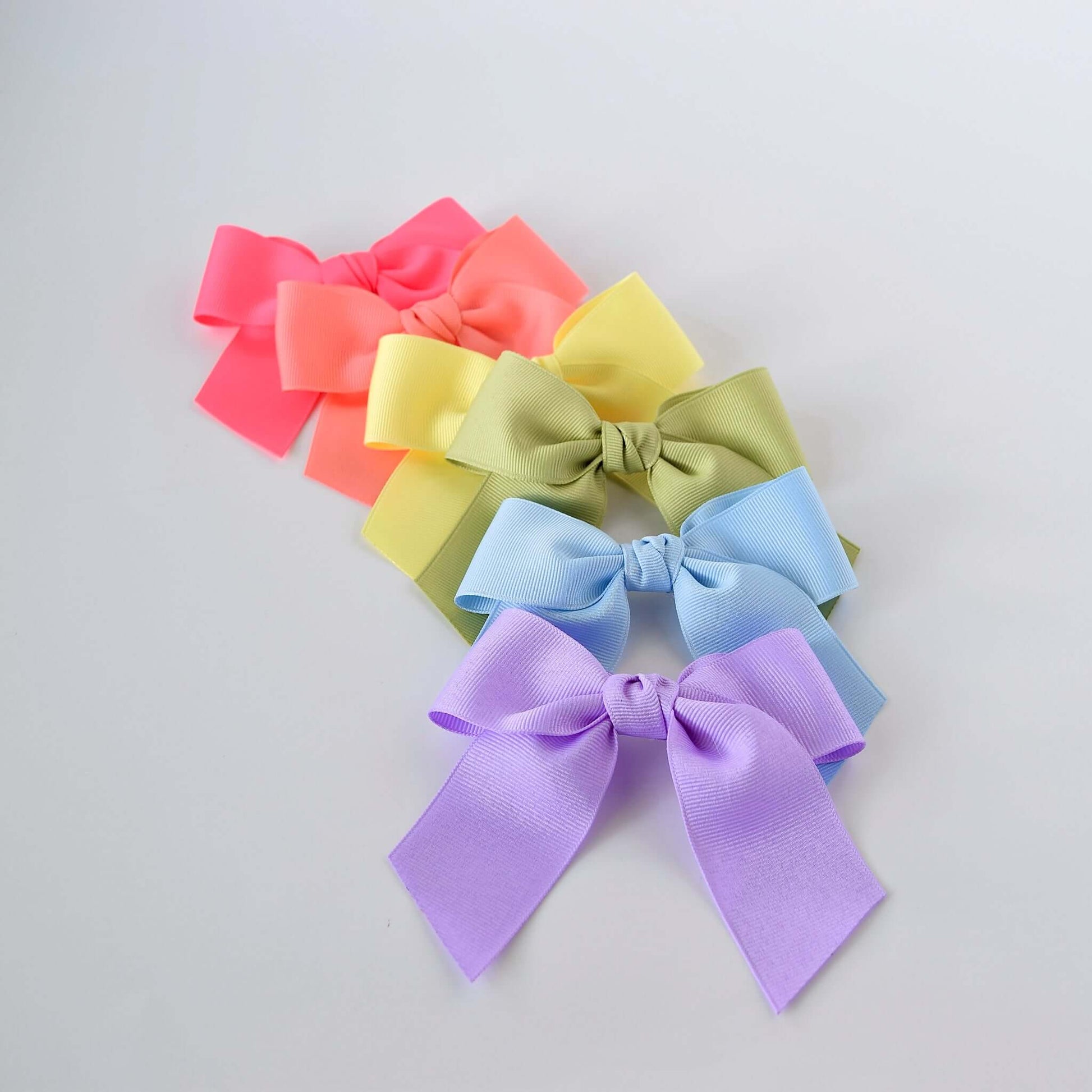 Colorful 4 inch grosgrain Sailor hair bows in pastel shades of pink, coral, yellow, green, blue, and lavender, arranged in a row.