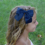 Girl wearing 5 inch sailor bow in navy blue in the side of her hair.