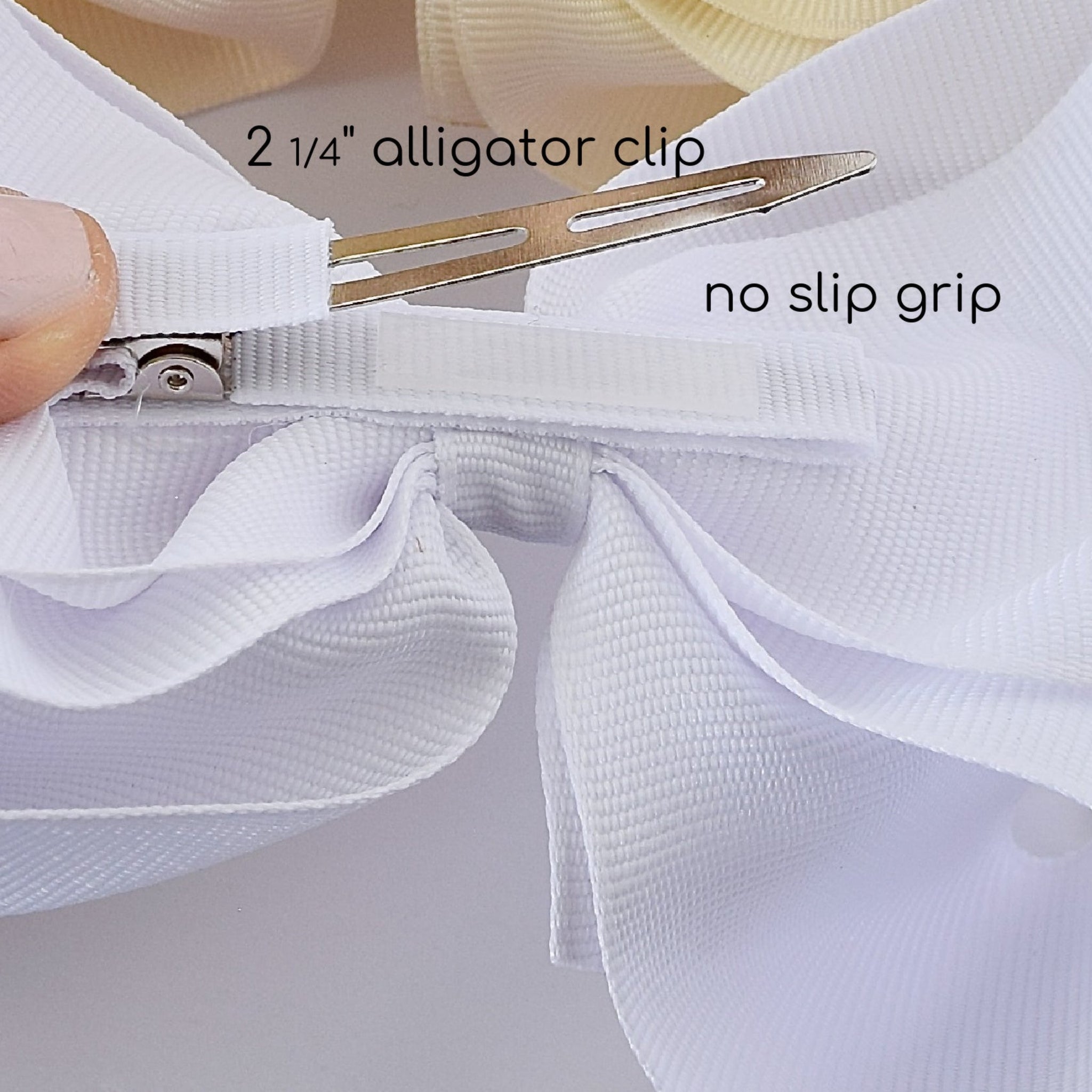 Alligator clip with white ribbon and text indicating size and feature