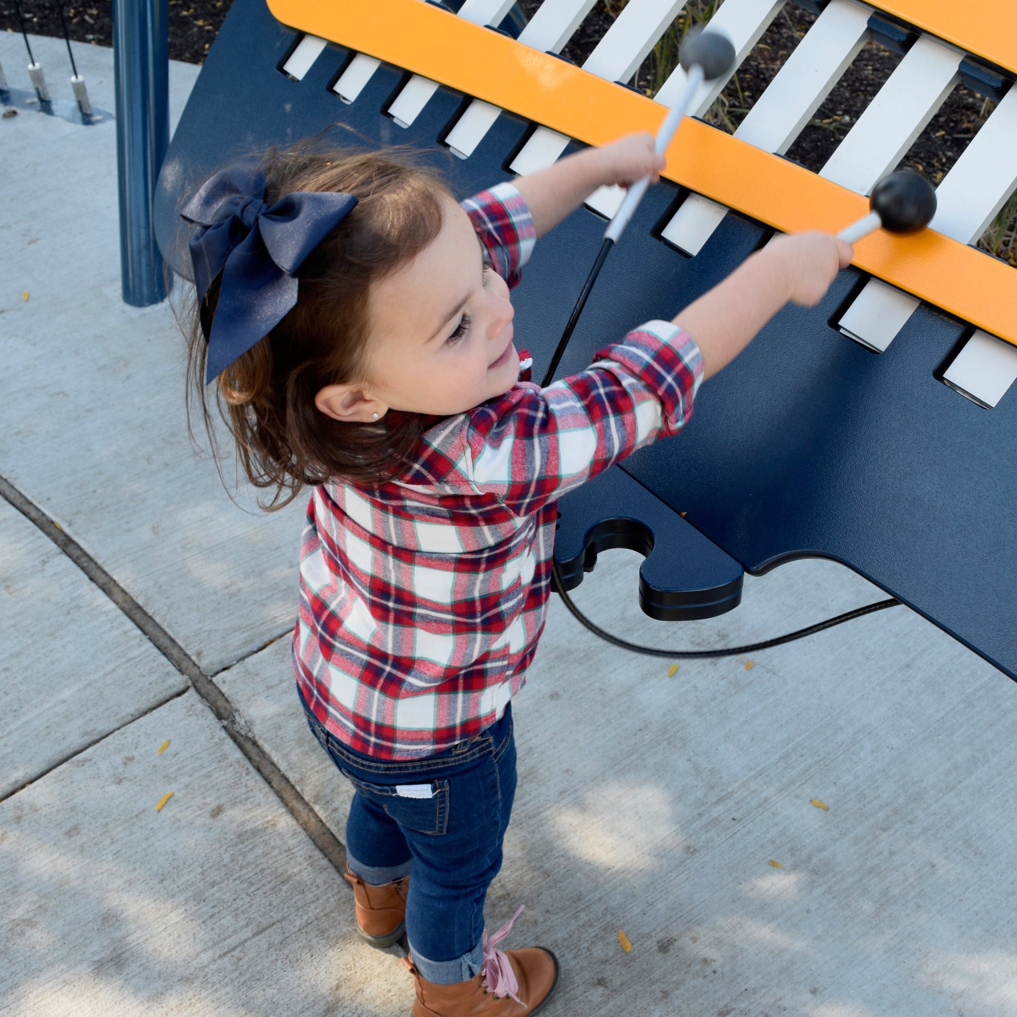 Child playing on a playground piano wearing navy 5 inch sailor bow in her hair.