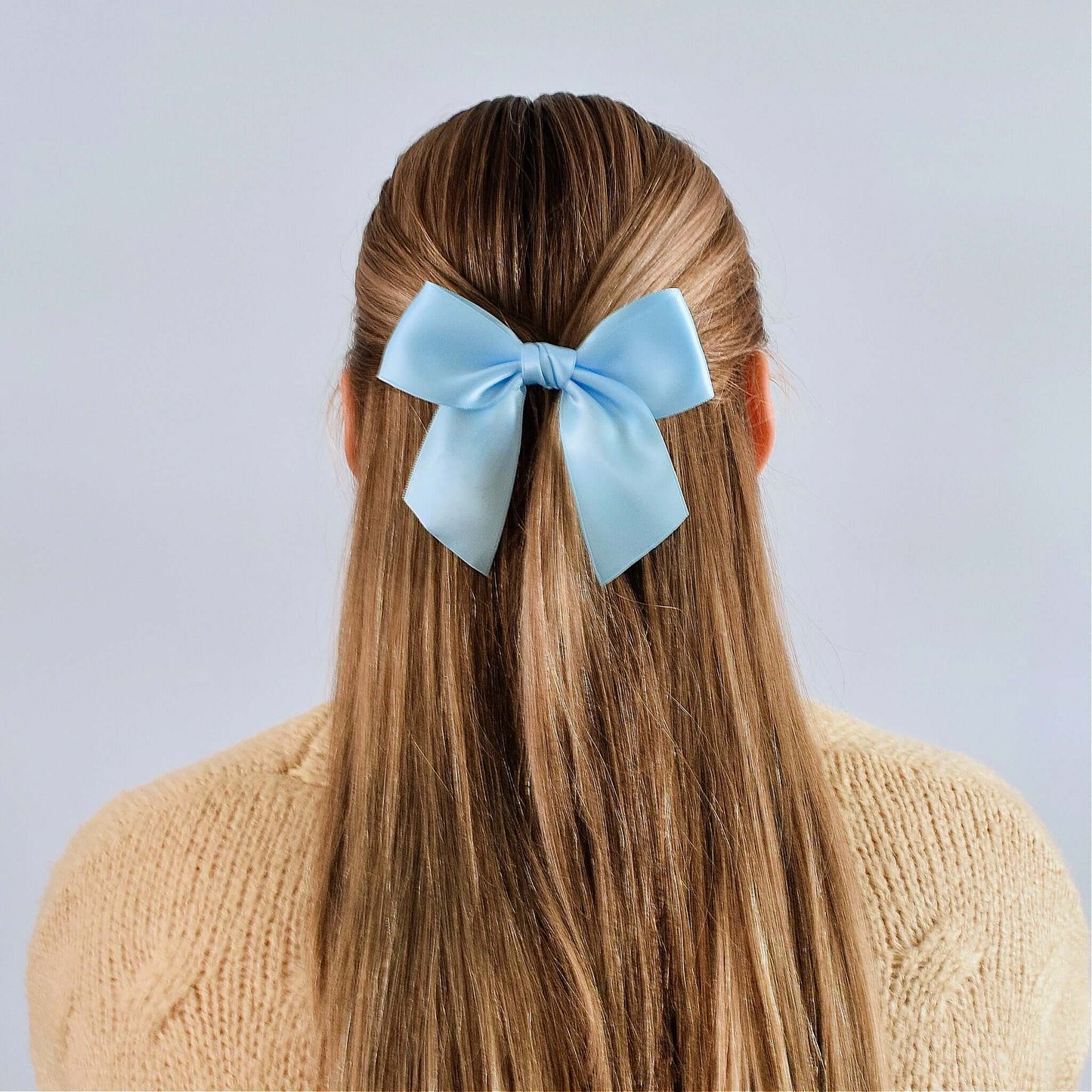 Blonde girl wearing a light blue grosgrain sailor hair bow with long straight hair, back view