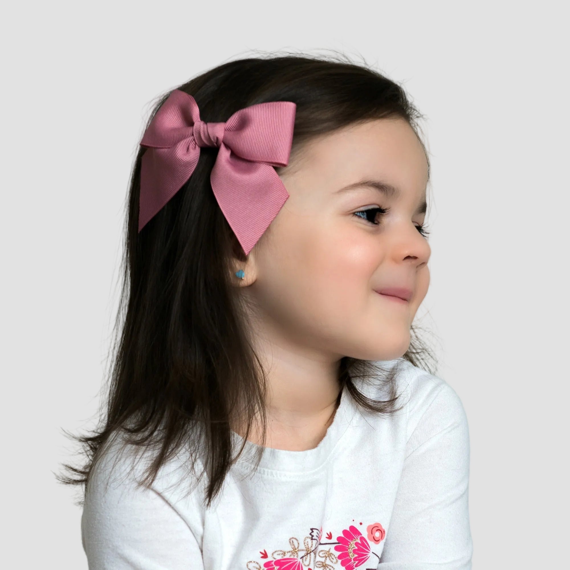 Young girl wearing 4 inch sailor bow in her hair against a plain background