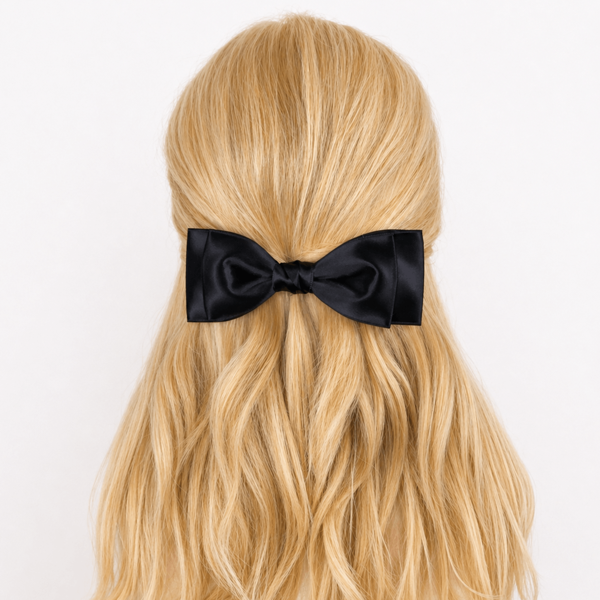Black Ava bow in blonde hair against a neutral background