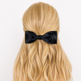 Black Ava bow in blonde hair against a neutral background