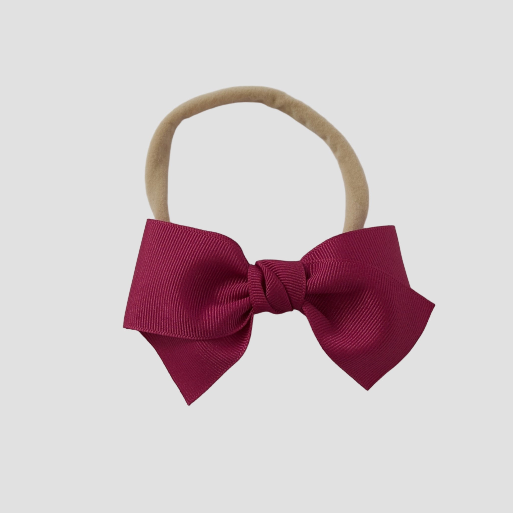 Azalea grosgrain Kayla hair bow on a nude nylon headband against a white background