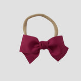 Azalea grosgrain Kayla hair bow on a nude nylon headband against a white background