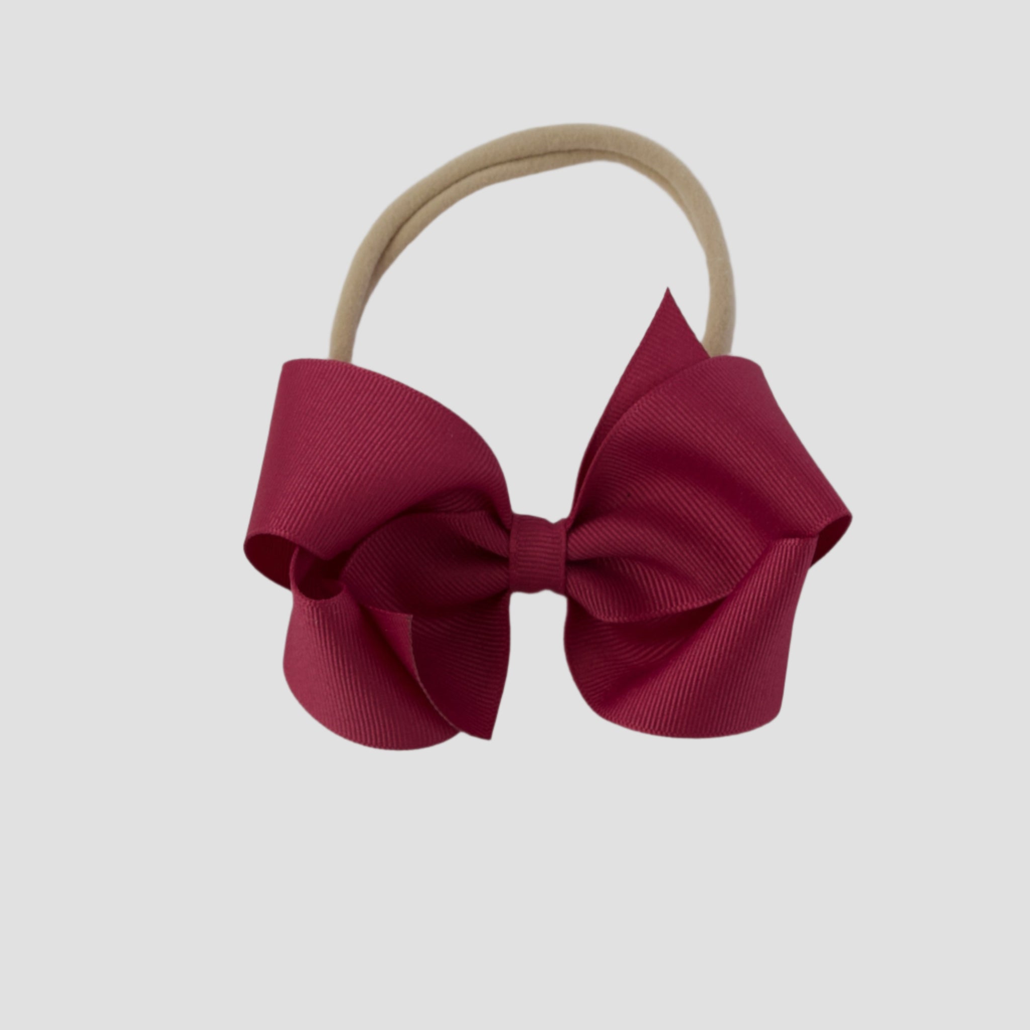 Azalea hair bow on a nude nylon band against a white background
