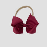 Azalea hair bow on a nude nylon band against a white background