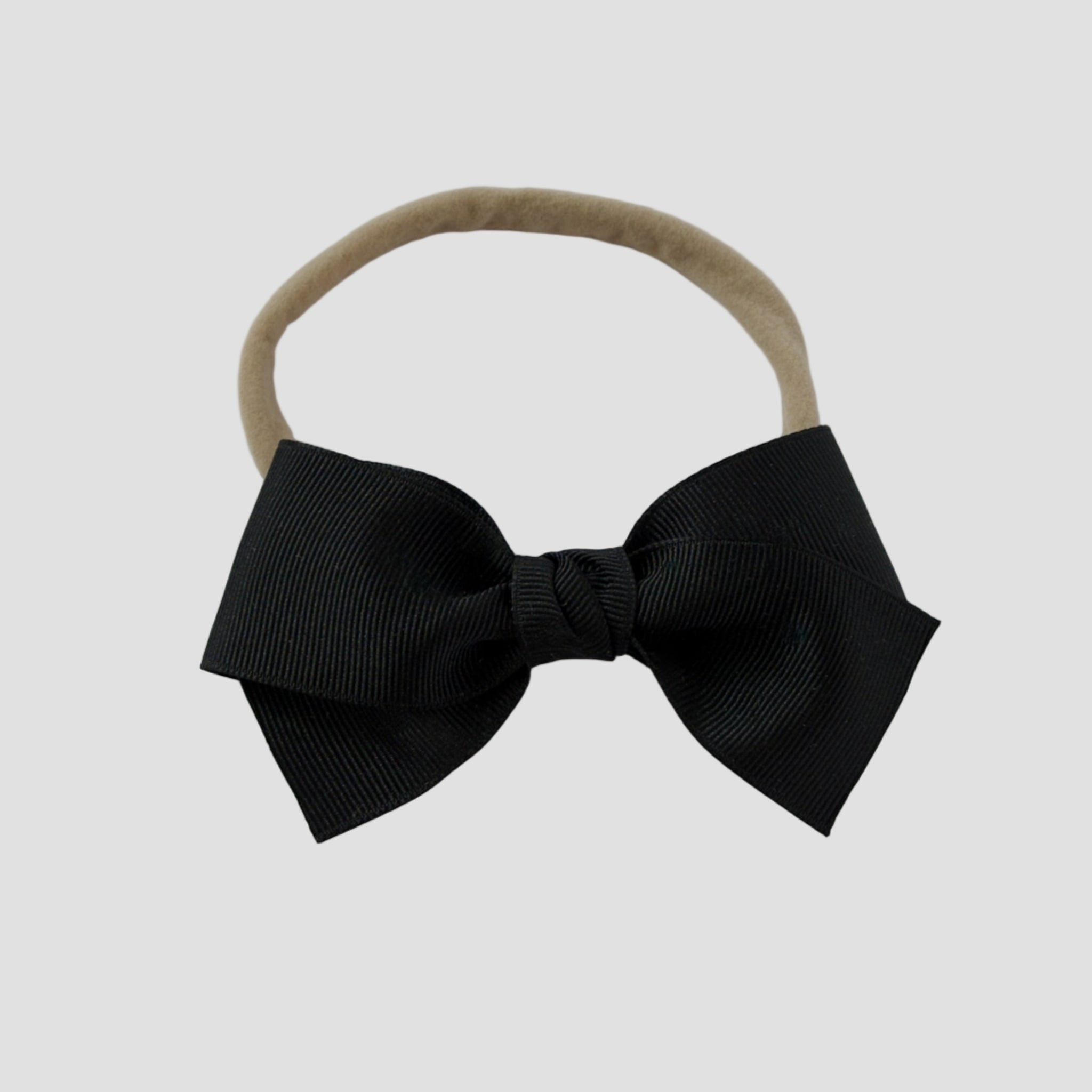 Black grosgrain Kayla hair bow on a nude nylon headband against a white background