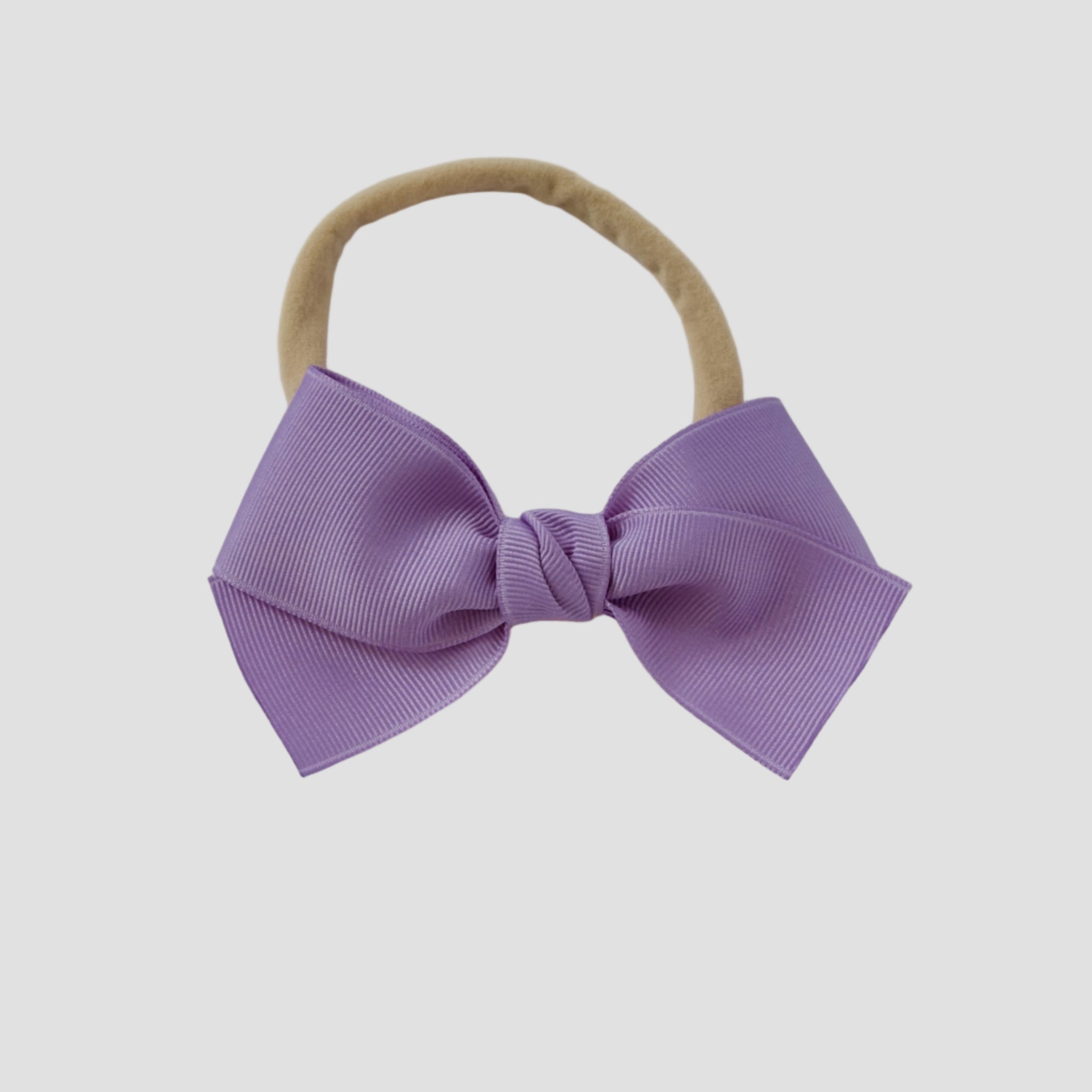 Dark orchid grosgrain Kayla hair bow on a nude nylon headband against a white background