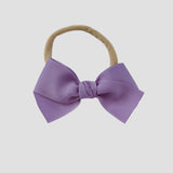 Dark orchid grosgrain Kayla hair bow on a nude nylon headband against a white background