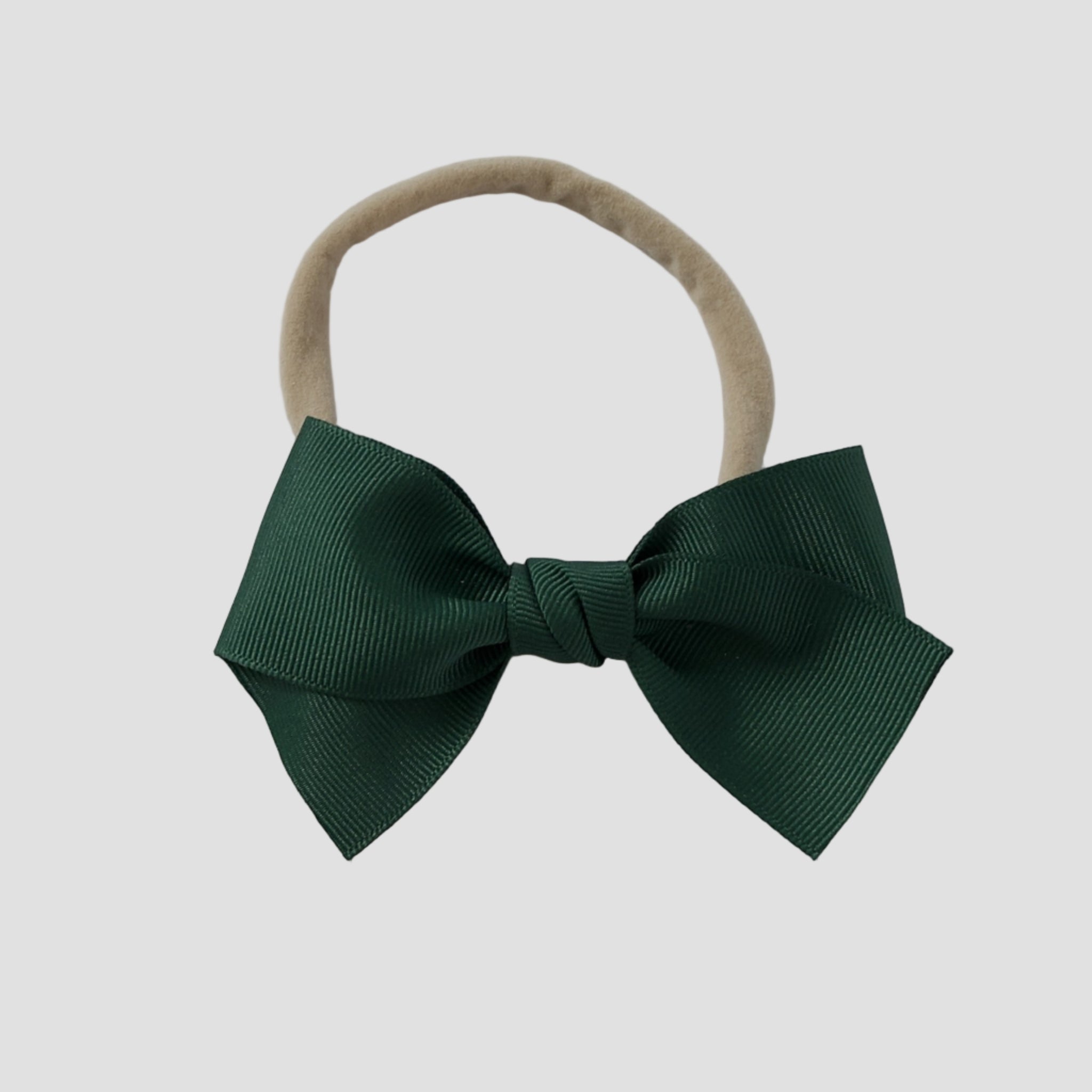 Forest green grosgrain Kayla hair bow on a nude nylon headband against a white background
