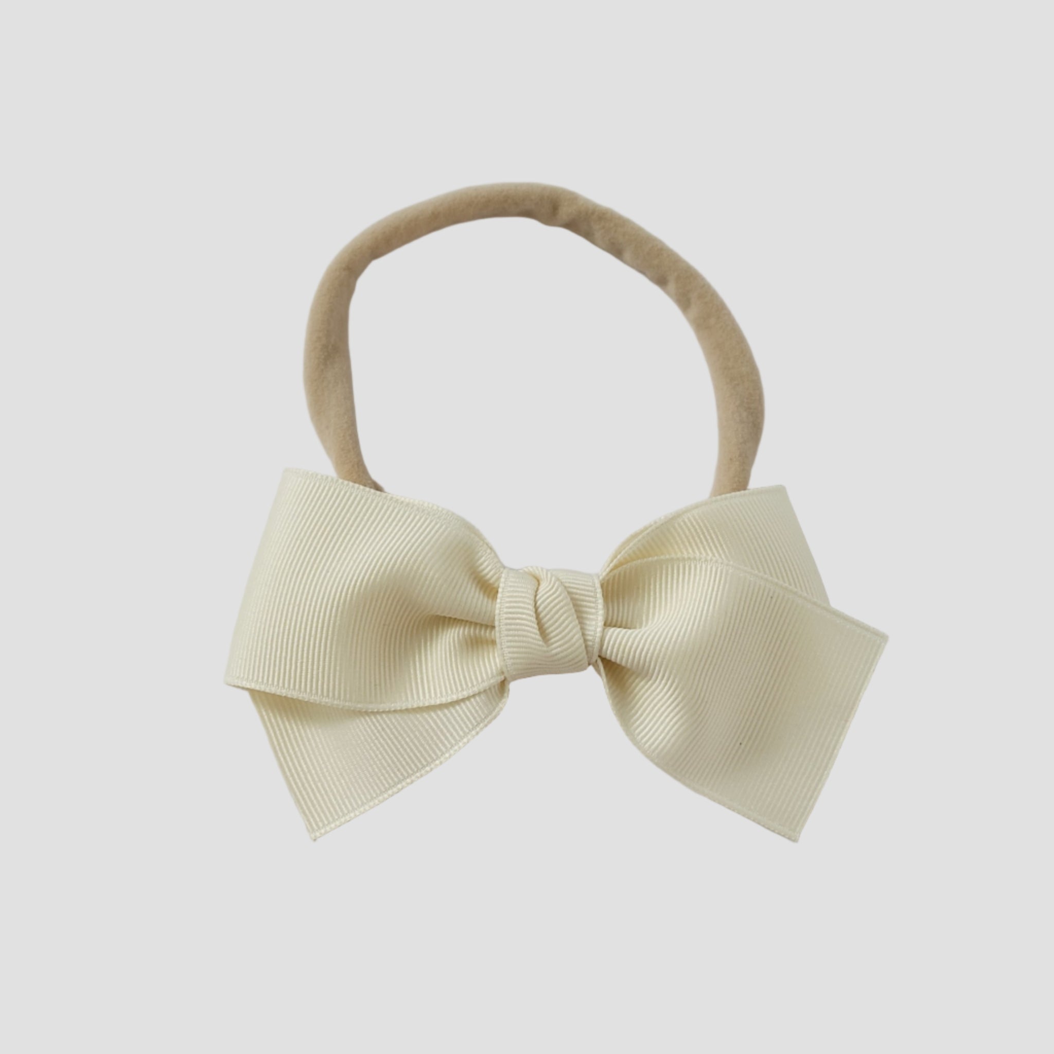 Ivory grosgrain bow on a nude nylon headband on a white background