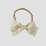 Ivory grosgrain bow on a nude nylon headband on a white background