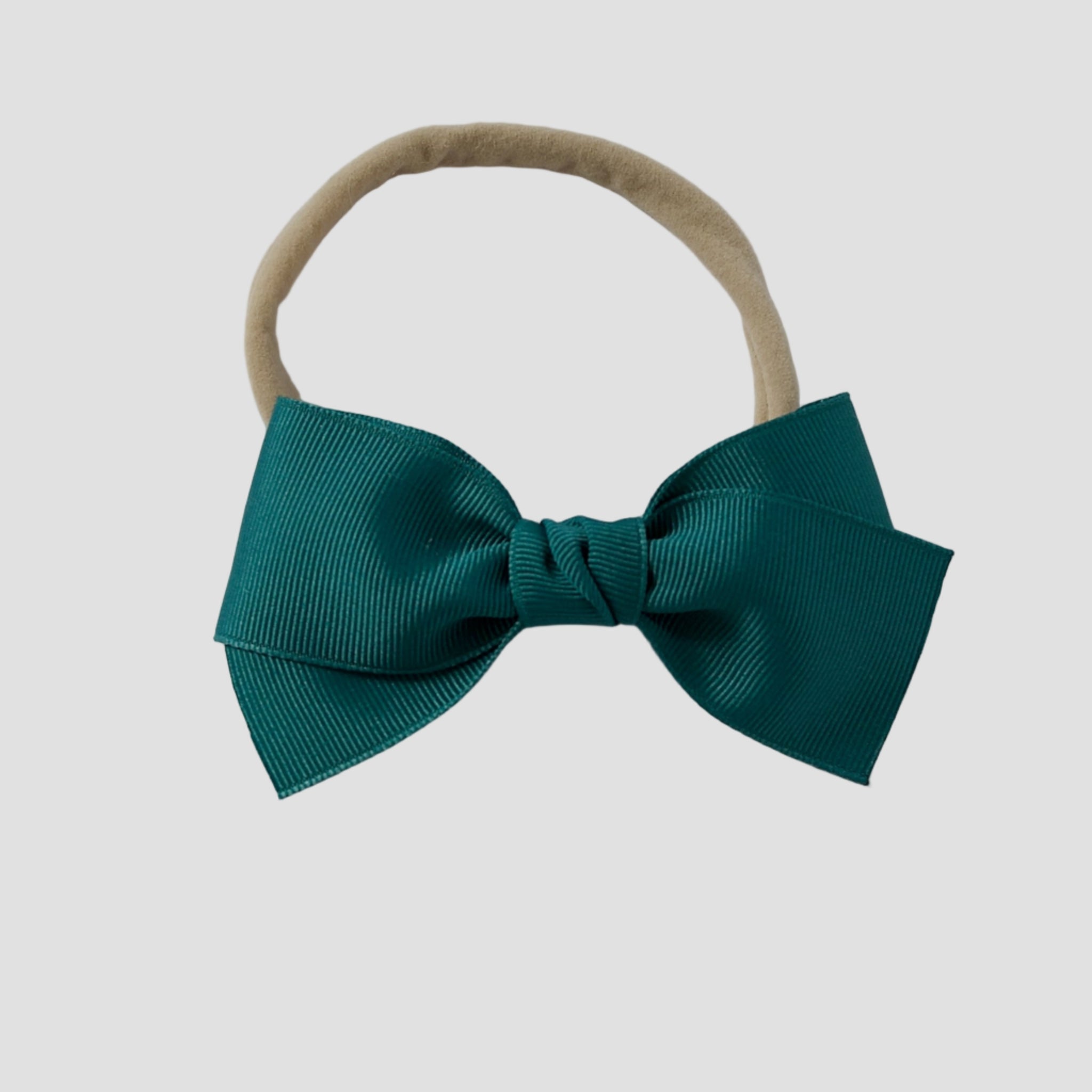 Jade green grosgrain Kayla hair bow on a nude nylon headband against a white background