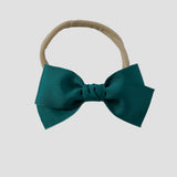 Jade green grosgrain Kayla hair bow on a nude nylon headband against a white background