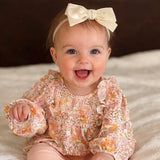 Baby wearing a floral dress and  Ivory velvet Kayla bow headband.