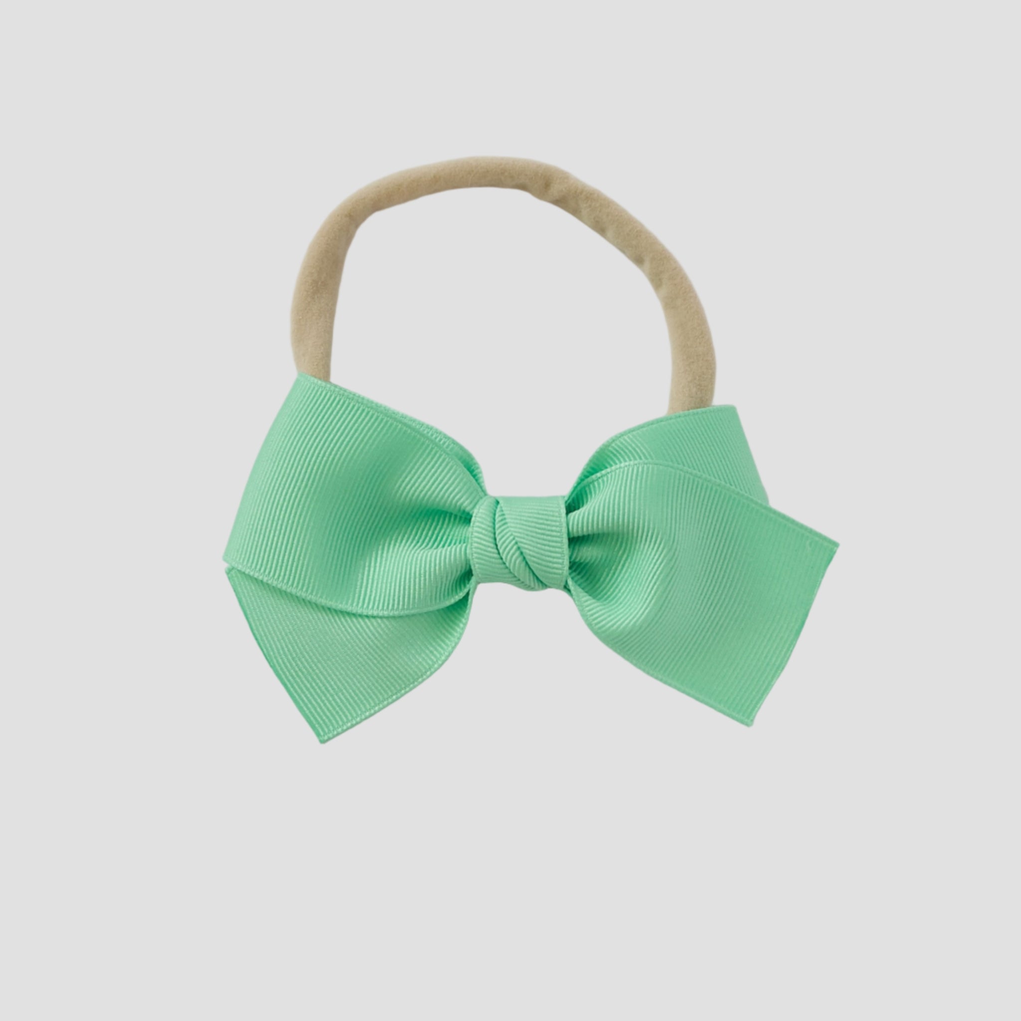 Mint grosgrain Kayla hair bow on a nude nylon headband against a white background
