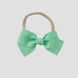 Mint grosgrain Kayla hair bow on a nude nylon headband against a white background
